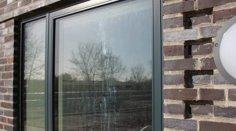 Glas, der er ætset af basisk vand fra murværket ovenover