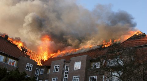 En boligejendom, hvor en brand har bredt sig til hele tagetagen.