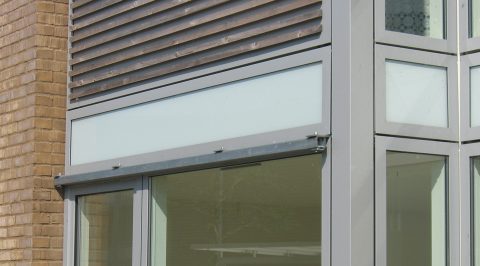 Let facade med glasbeklædte partier ud for etageadskillelsen.